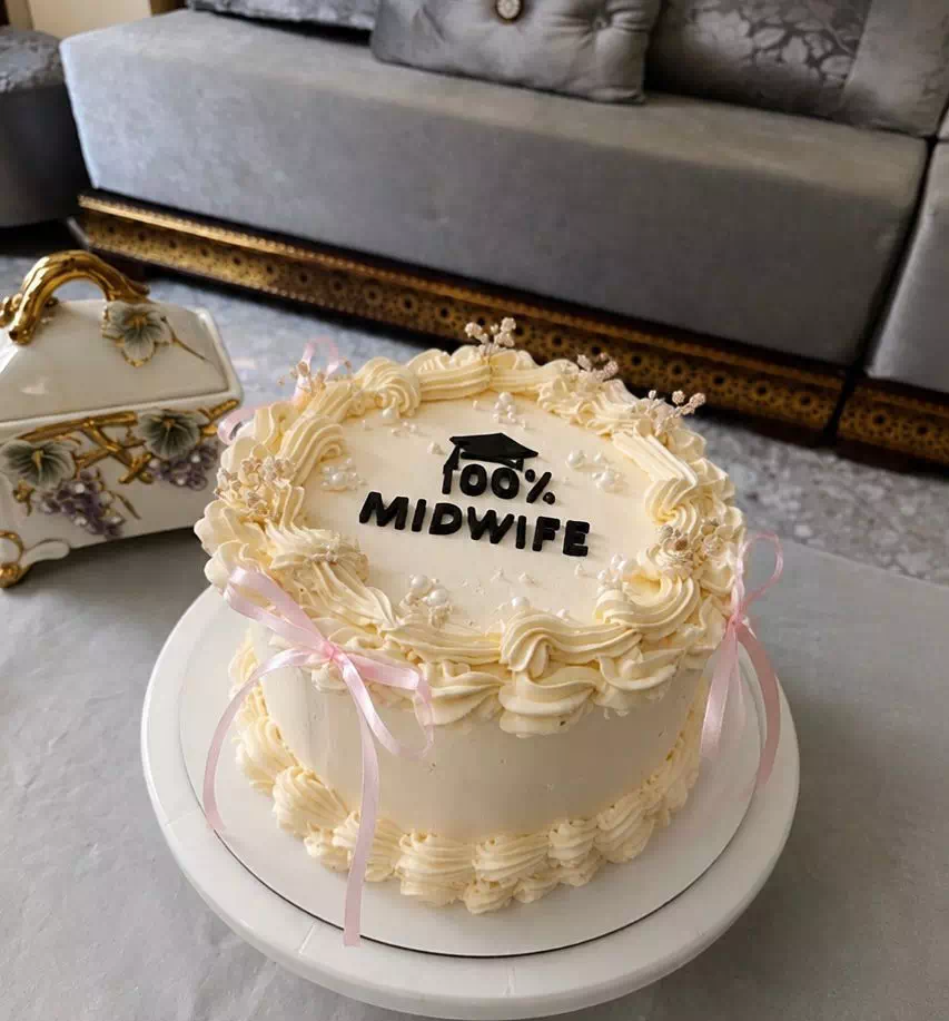 Gâteau ivoire pour remise de diplôme de sage-femme, rubans roses et lettrage « 100% Midwife », création MANGO DZ à Oran