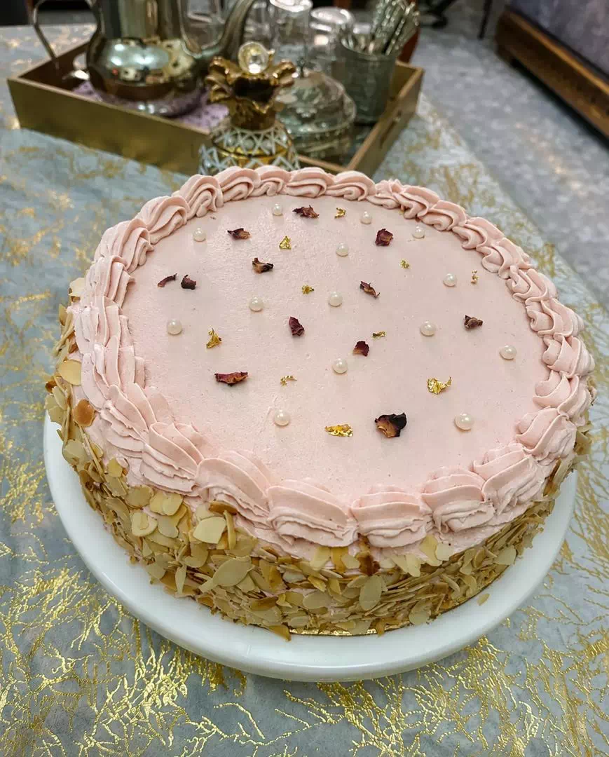 Gâteau à la crème rose façon fraisier, contour en amandes effilées et pétales de rose, création MANGO DZ à Oran