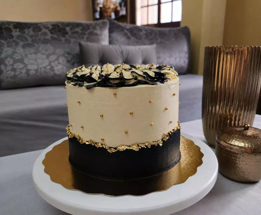 Gâteau bicolore noir et crème avec feuille d'or et fleurs en pochage, création MANGO DZ à Oran