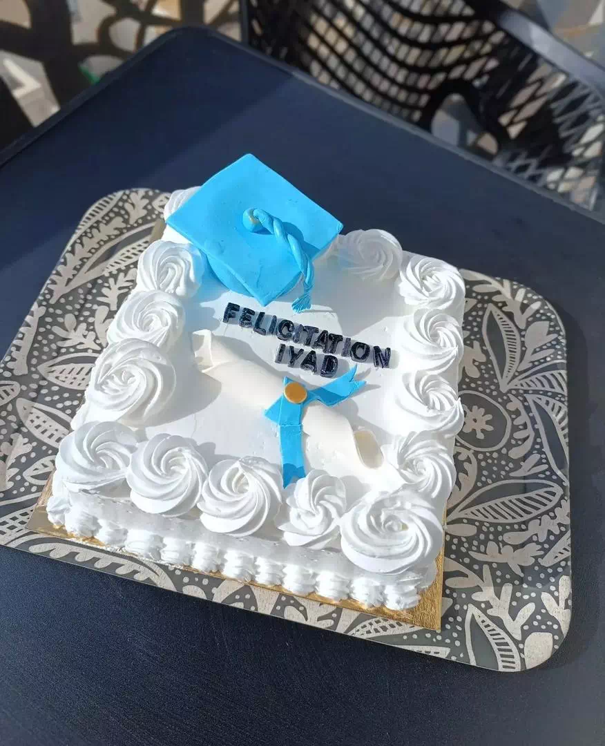 Gâteau carré blanc de remise de diplôme avec toque bleue en pâte à sucre et lettrage personnalisé, création MANGO DZ à Oran